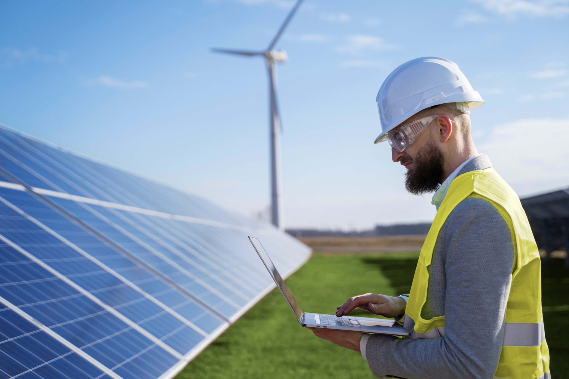 An engineer with a tablet in hand standing in the middle of a field.